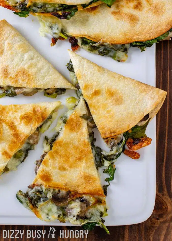 overhead shot of Baked and cut Spinach Mushroom Sheet Pan Quesadillas on a sheet pan lined with white parchment paper