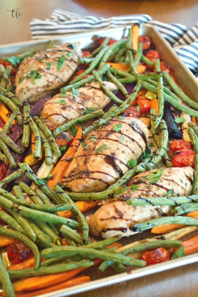 Maple Balsamic Chicken Breasts and Veggies on a sheet pan drizzled with balsamic glaze