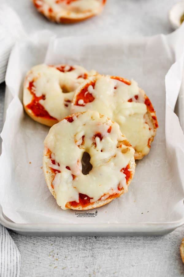 baked low calorie pizza bagels on a parchment paper lined quarter sheet pan ready to be served