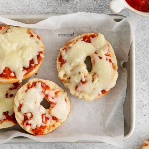 overhead shot of low calorie pizza bagels in a parchment paper lined quarter sheet pan