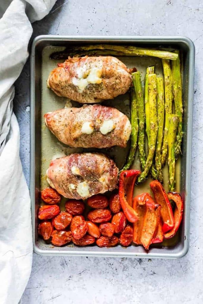 overhead shot of Sheet Pan Prosciutto Wrapped Chicken with Asparagus, red pepper, and tomatoes