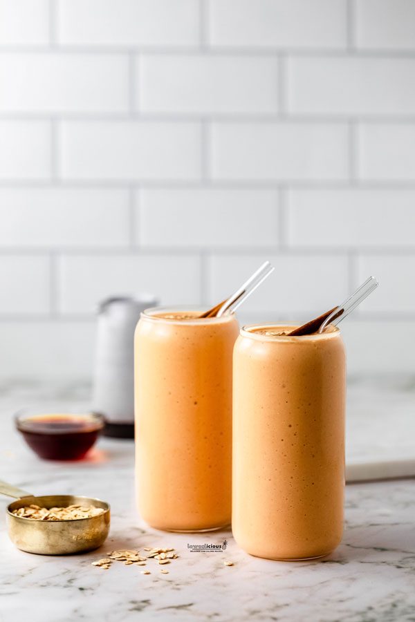 straight on shot of two pumpkin smoothies in tall clear glasses with glass straws