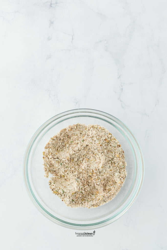 a bowl of ranch seasoning mix with smoked paprika, dried oregano, and black pepper mixed together in a small glass bowl