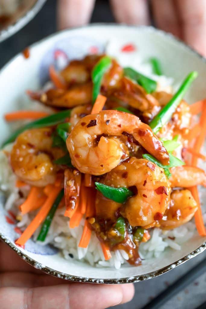 closeup of honey garlic shrimp over rice with scallions and julienned carrots