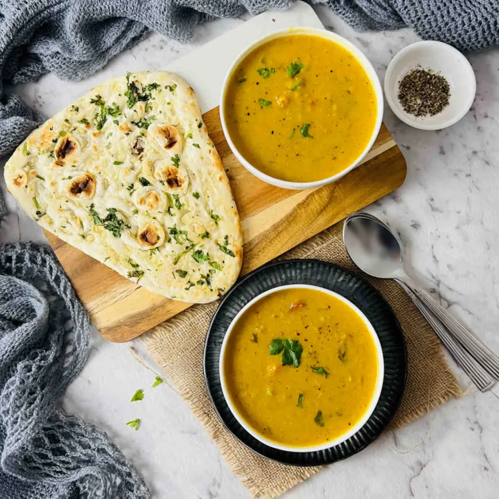 overhead shot of overhead shot of Instant Pot Mulligatawny Soup in 2 white bowls with naan
