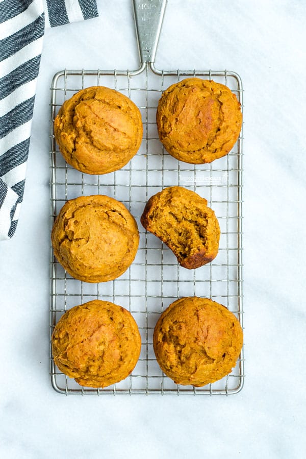 overhead shot of 6 low calorie pumpkin muffins with cake mix on a small wire rack. 1 has a bite taken out