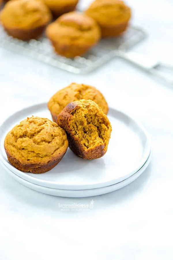 3 Low Calorie Pumpkin Muffins with Cake Mix on a small round white plate. 1 has a bite taken out