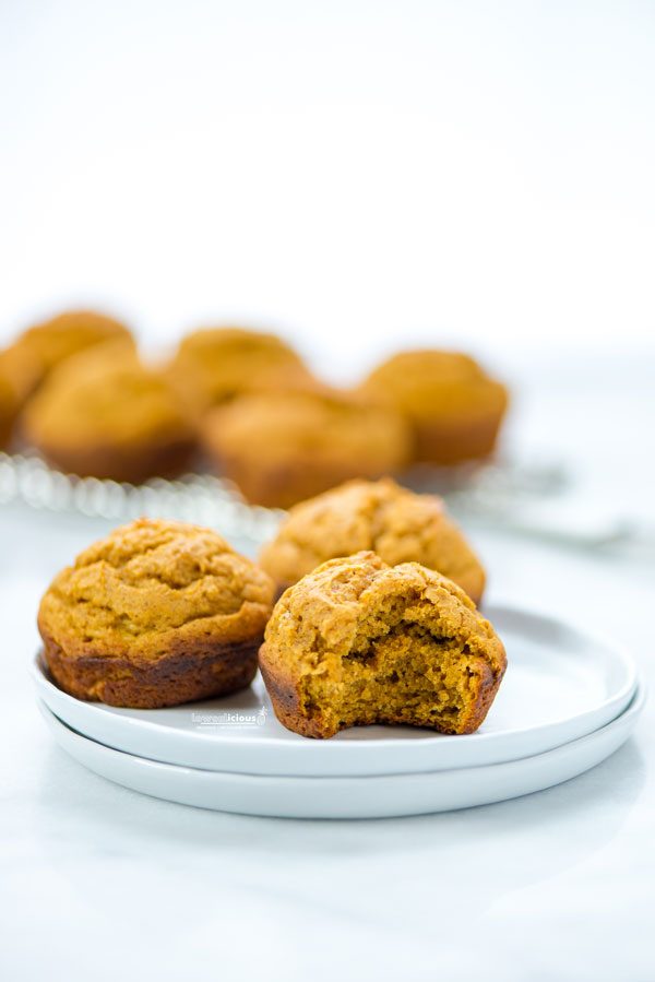 3 Low Calorie Pumpkin Muffins with Cake Mix on a stack of small white plates. 1 muffin has a bite taken out.