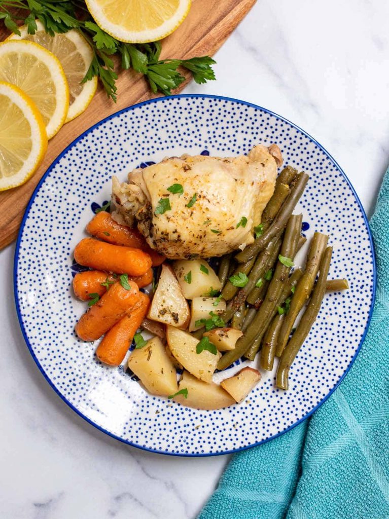 Slow Cooker Chicken Thighs and Vegetables with Herbs plated on a round patterned blue plate