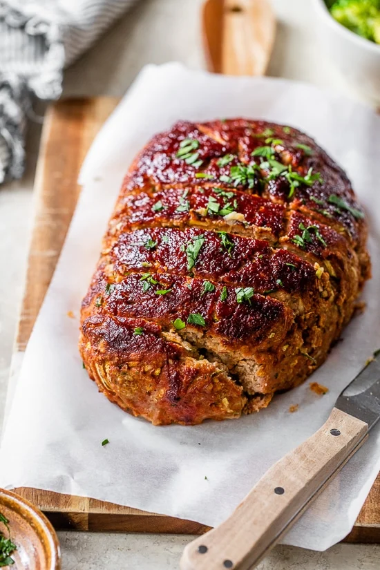a baked Turkey Meatloaf with Zucchini on a white parchment paper lined wood cutting board