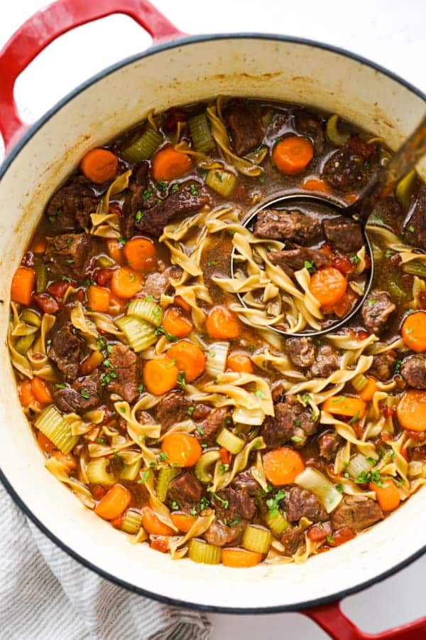a pot of Beef Noodle Soup in a red and white Dutch Oven