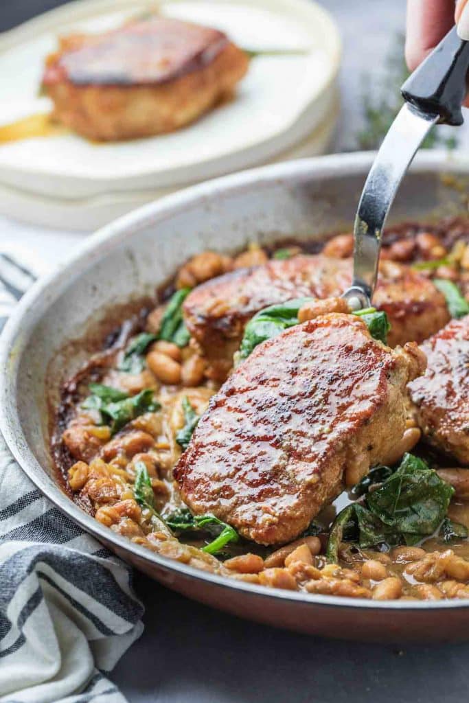 Pork Chop Skillet Dinner with Spinach and White Beans in a large stainless steel skillet