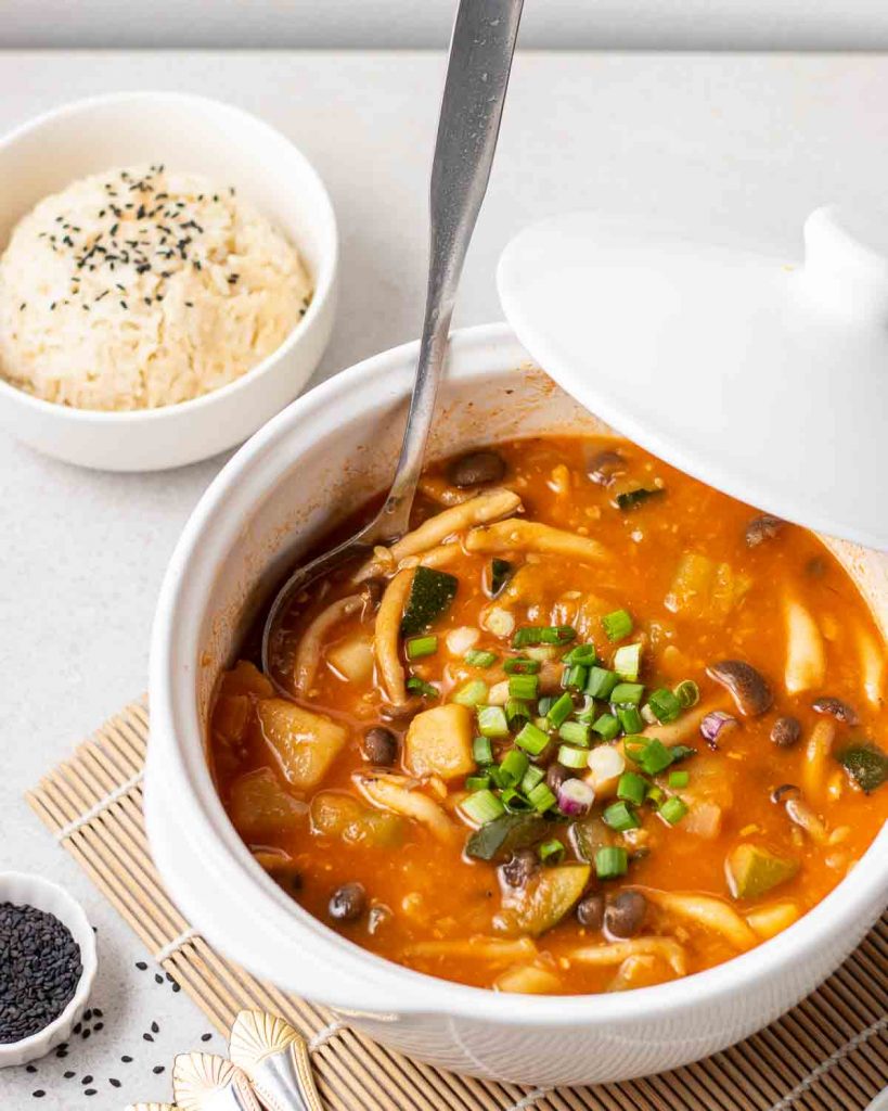 Korean Gochujang Soup (Gochujang Stew) in a small white pot with a silver spoon