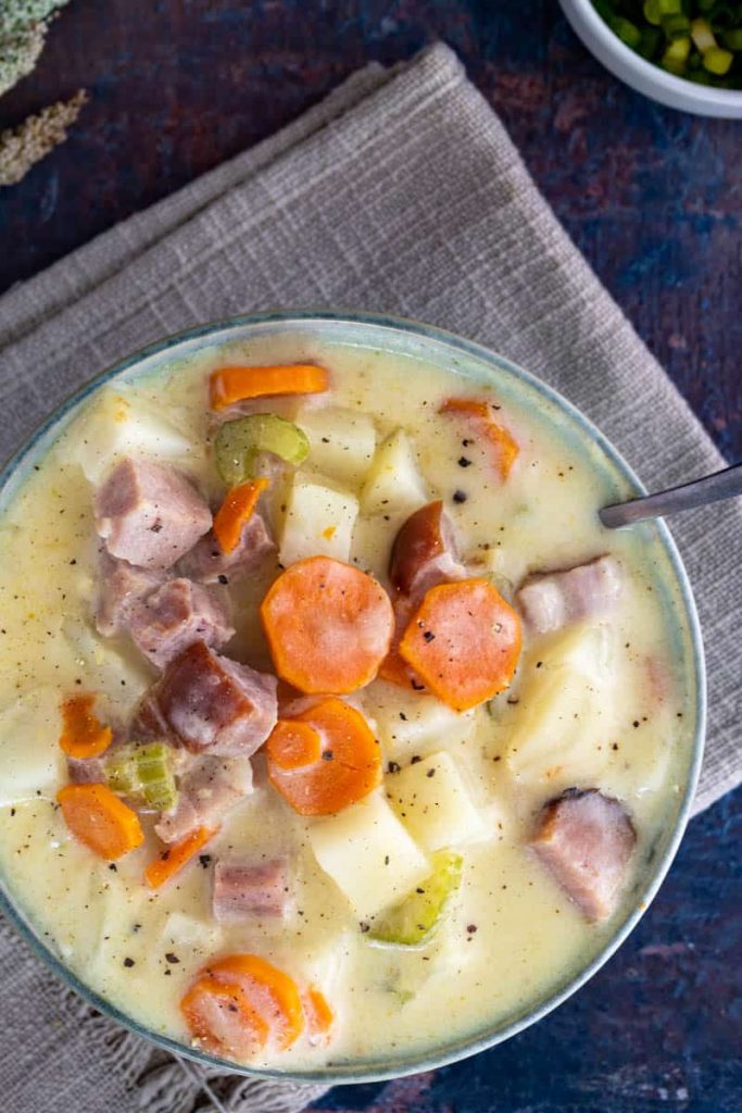 overhead shot of Crock Pot Ham and Potato Soup in a bowl with a silver spoon