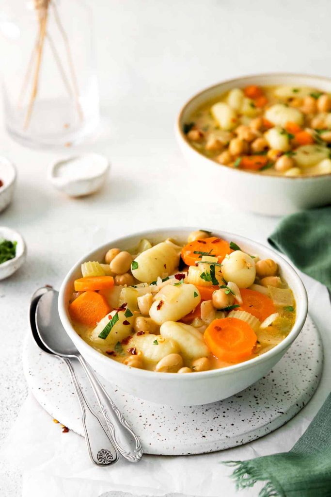 Vegetable Gnocchi Soup in a white bowl with a silver soup