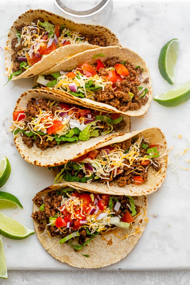 overhead shot of ground beef tacos in tortillas lined up - one of the recipes for this week's healthy weekly meal plan
