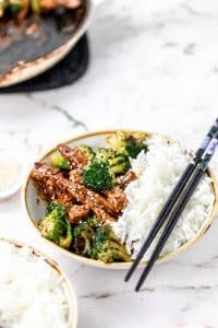 healthy beef and broccoli stir fry recipe plated in a small bowl with white rice on one side