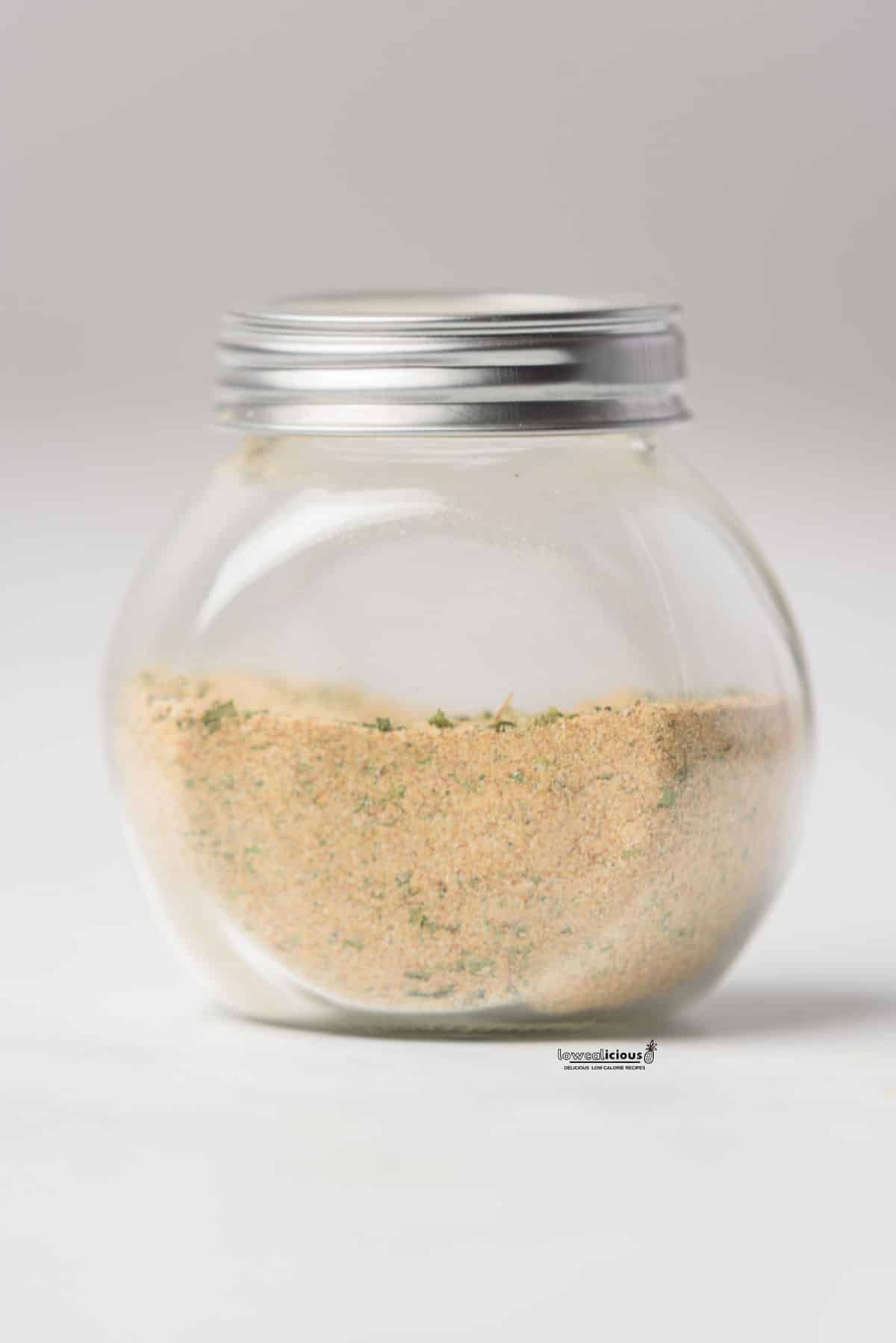 a homemade chicken seasoning recipe (chicken rub) stored in a clear glass jar with a silver screw-on top