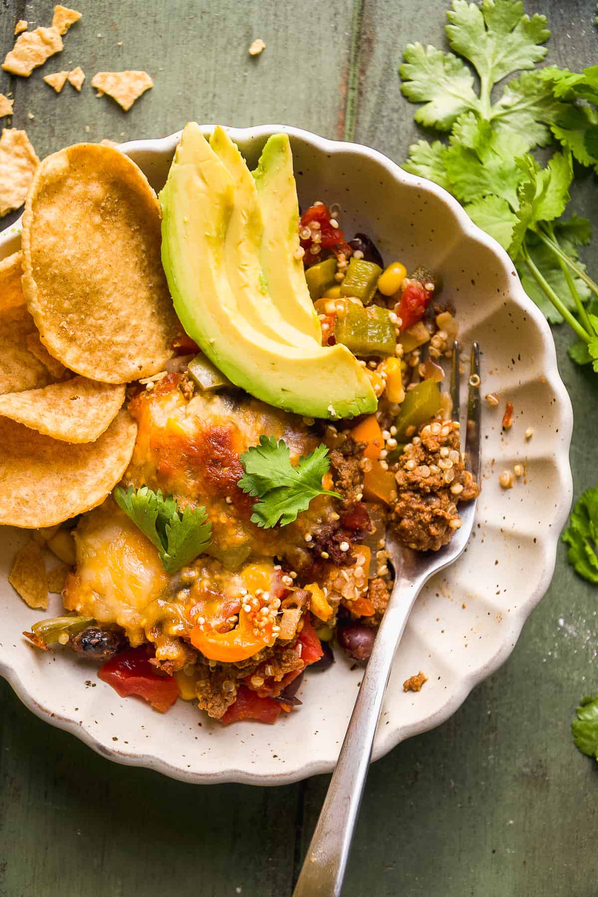 overhead shot of healthy Taco Casserole in a scalloped bowl with a fork garnished with sliced avocado and tortilla chips - one of the recipes for this week's healthy weekly meal plan