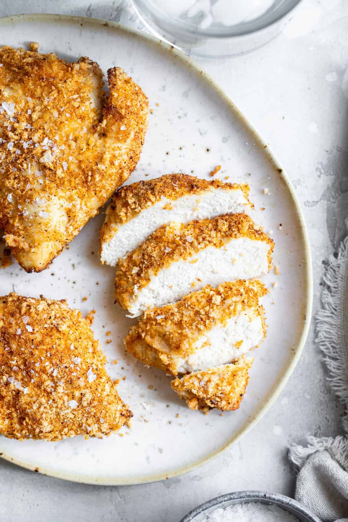 cooked Crispy Air Fryer Chicken Breast sliced on a round white plate - one of the recipes for this week's healthy weekly meal plan