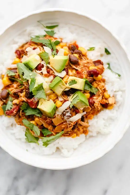 overhead shot of Crock Pot Chicken Taco Chili in a white bowl over white rice and topped with avocado - one of the recipes for this week's healthy weekly meal plan