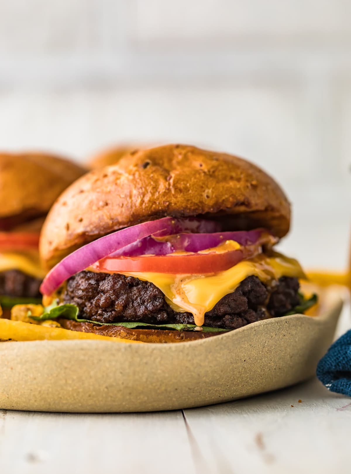 grilled juicy burgers on a buns with cheese, tomato, and red onion - one of the recipes for this week's healthy weekly meal plan