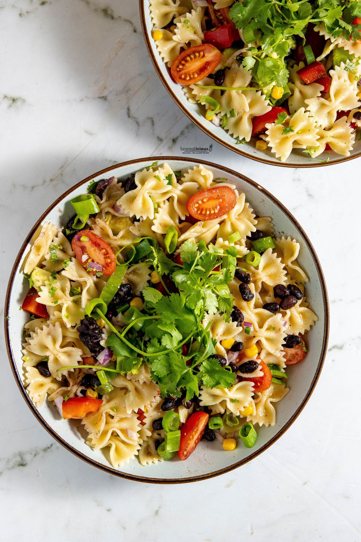 Healthy Southwest Pasta Salad recipe (Vegan) in white serving bowls with brown rim garnished with fresh cilantro