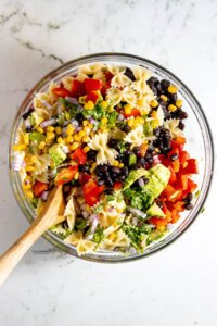 Healthy Southwest Pasta Salad recipe (Vegan) mixed together in a large glass bowl with a wood spoon