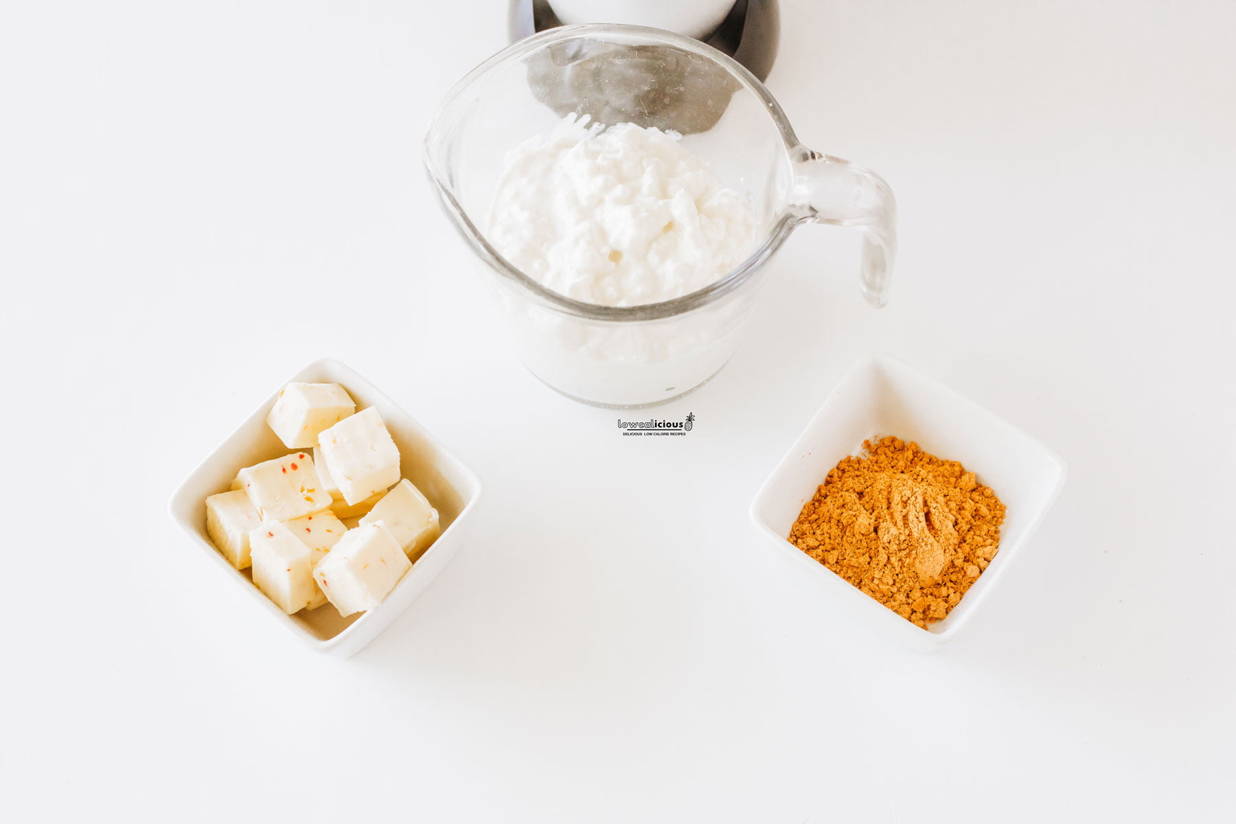horizontal image with the ingredients to make the  Viral TikTok Cottage Cheese Queso Dip in individual square white bowls with cottage cheese in a blender canister