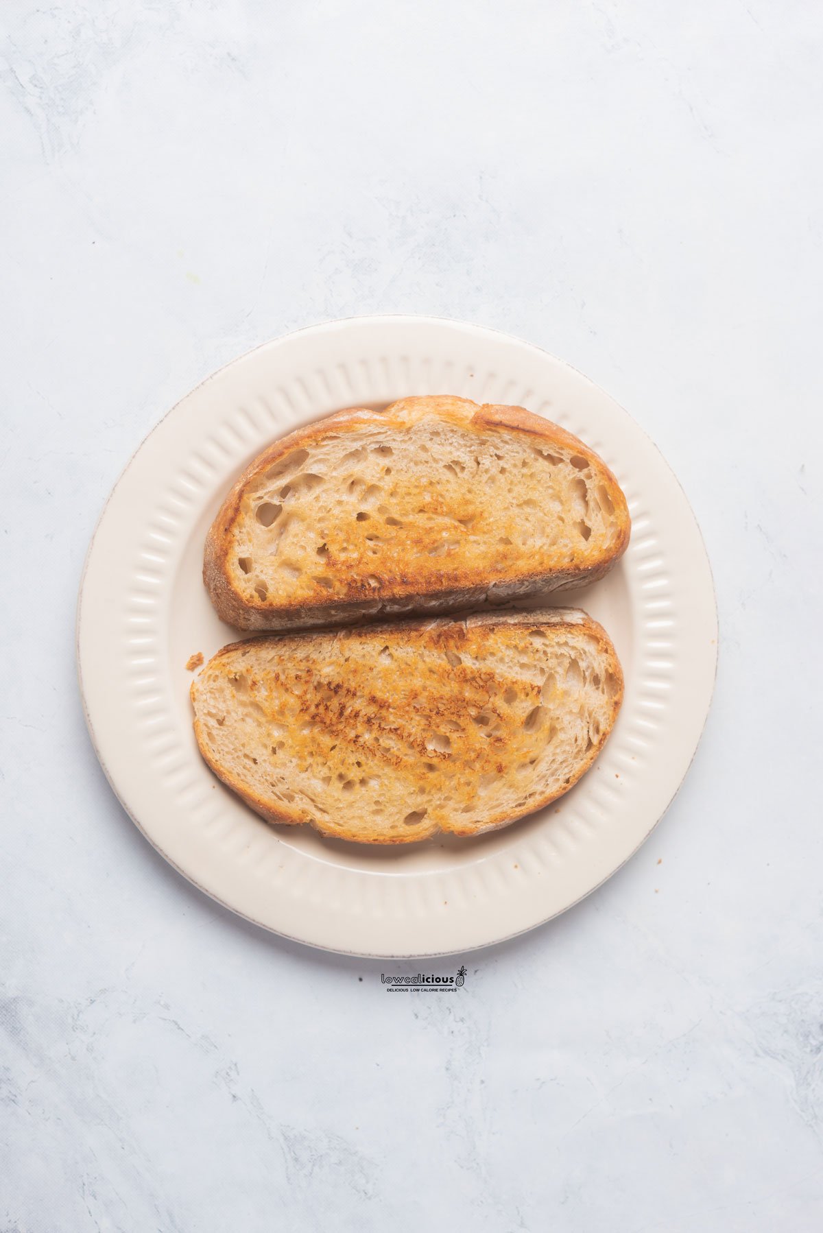 two slices of sourdough toast on a round white plate to serve with a Pesto Eggs recipe