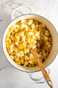 Onion, corn, jalapeno, potatoes, and garlic in a large white dutch oven to make a Vegan Corn Chowder Recipe