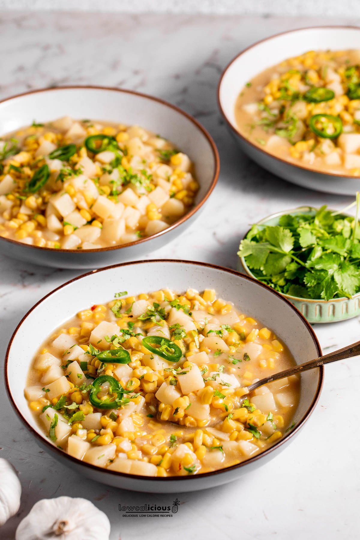 cooked Vegan Corn Chowder Recipe served in 3 white soup bowls with brown rims