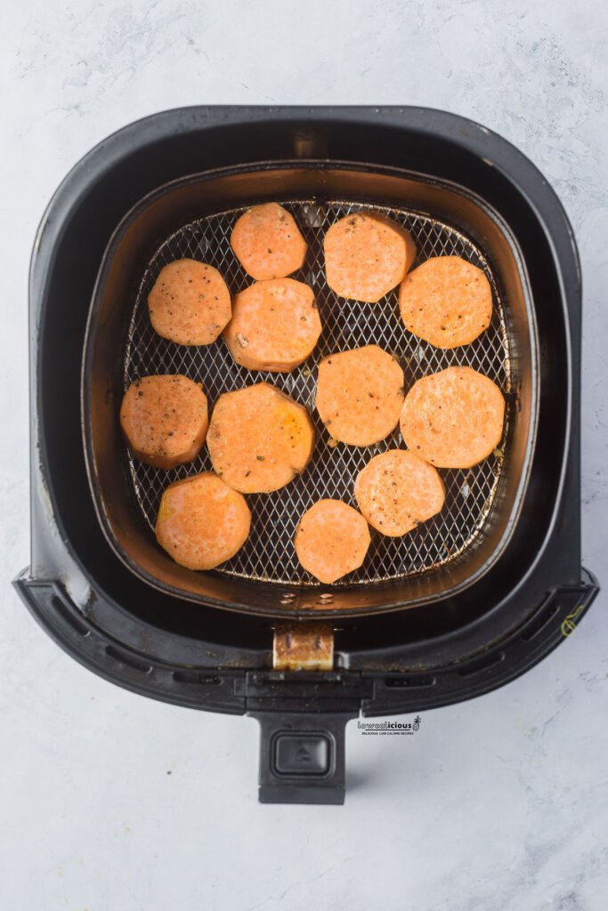 raw and seasoned sweet potato rounds in an air fryer basket ready to be cooked to make Viral Smashed Sweet Potatoes