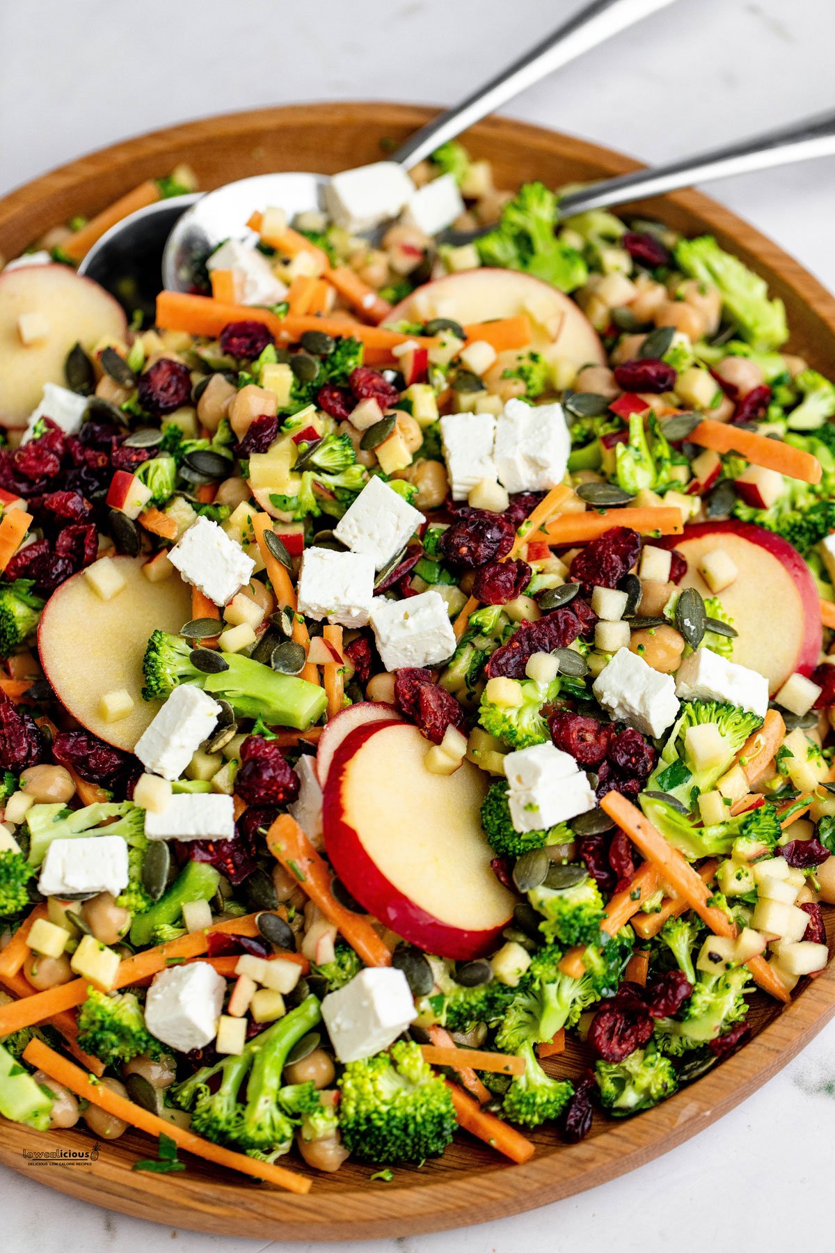 Healthy Broccoli Apple Salad Recipe with Cranberries in a large wood serving bowl with two serving spoons ready to serve