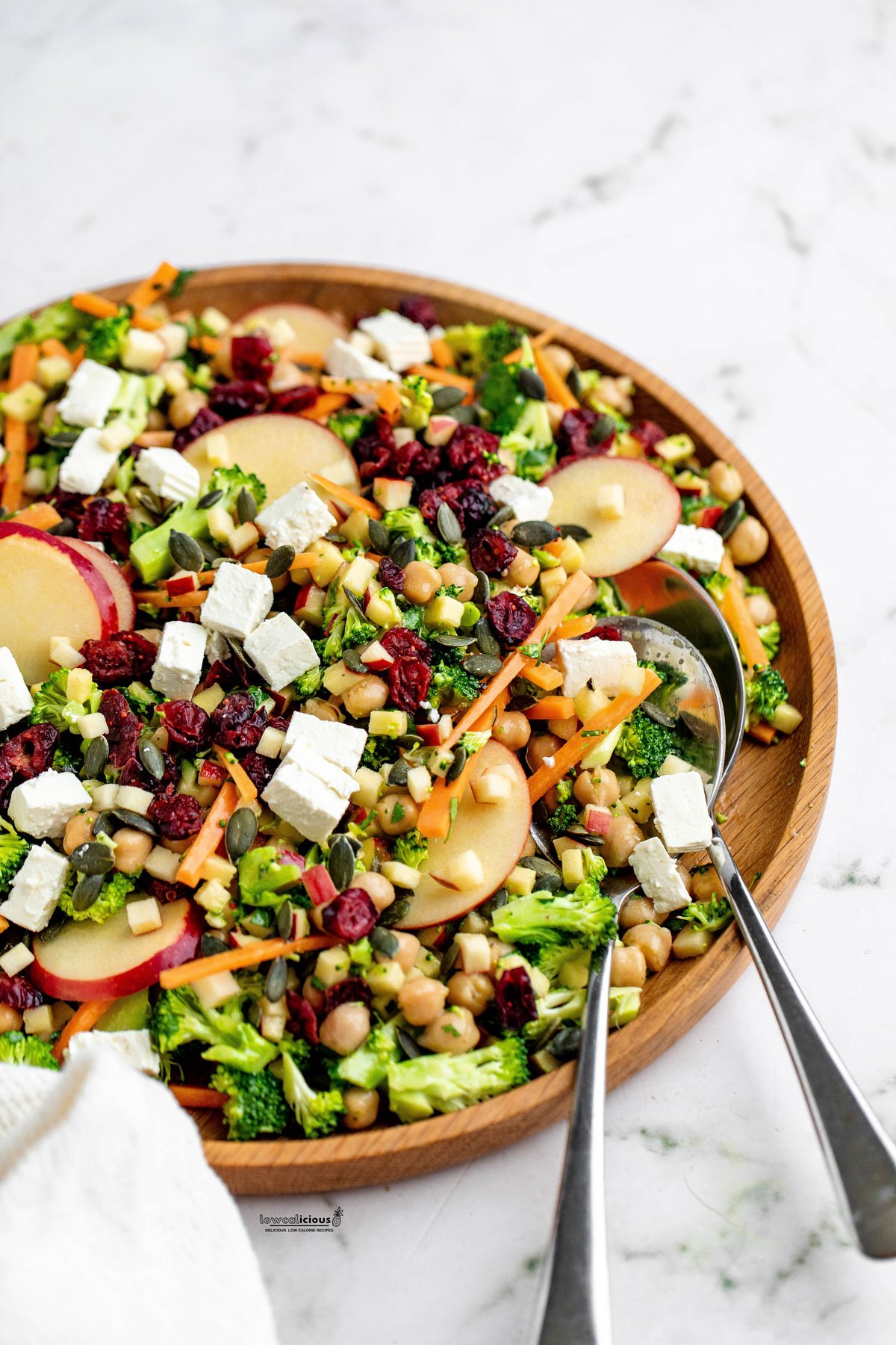 Healthy Broccoli Apple Salad Recipe with Cranberries in a wood serving bowl with two serving spoons
