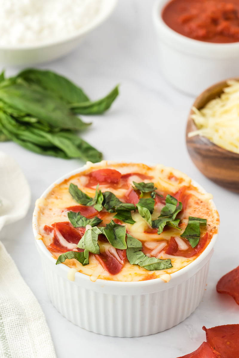 cooked Cottage Cheese Pizza Bowl (Viral TikTok Recipe) in a white ramekin topped with melted cheese and chopped fresh basil