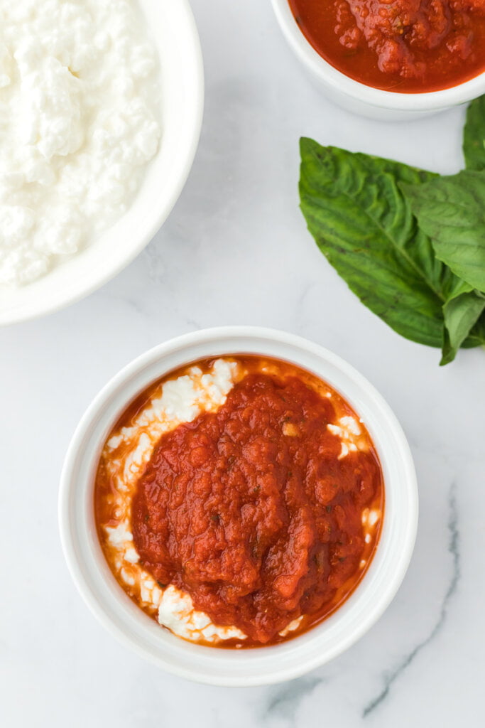 cottage cheese and marinara sauce in a white ramekin to make Viral TikTok Cottage Cheese Pizza Bowls