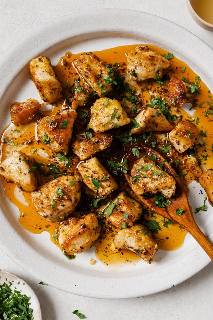 Garlic Butter Chicken Bites on a round white plate with a wood spoon - one of the recipes for this week's healthy weekly meal plan