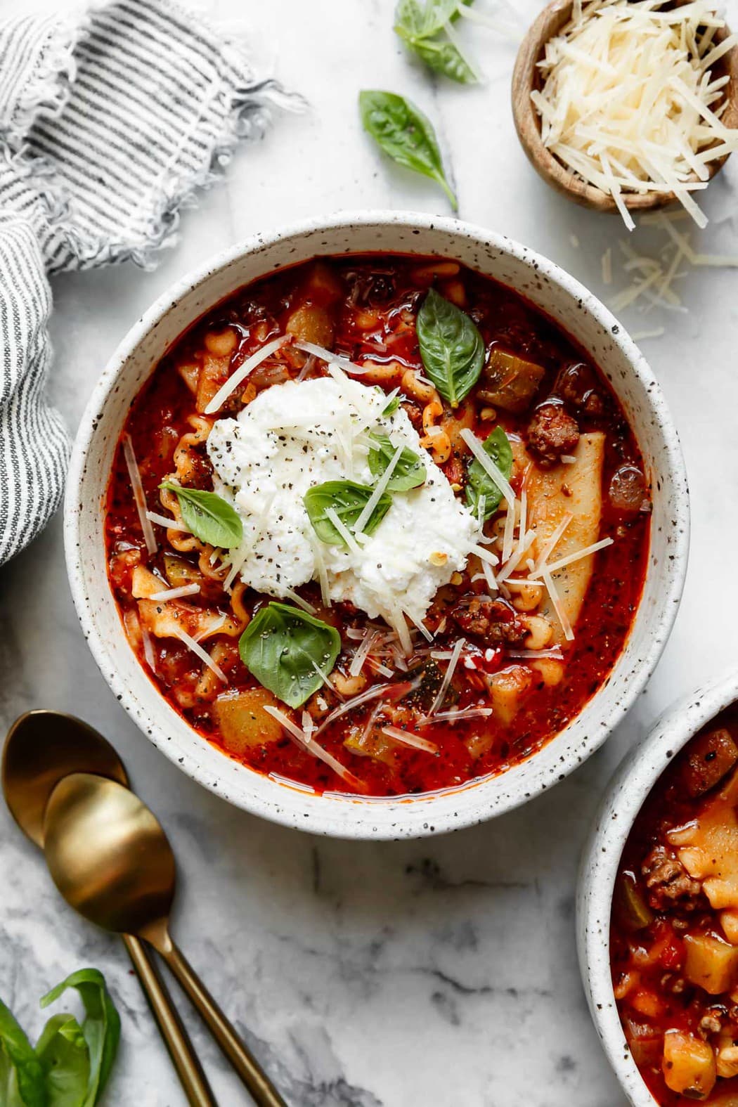 Instant Pot Lasagna Soup in a white pottery bowl topped with a dollop of ricotta cheese, shredded parmesan cheese, and fresh basil leaves - one of the recipes for this week's healthy weekly meal plan