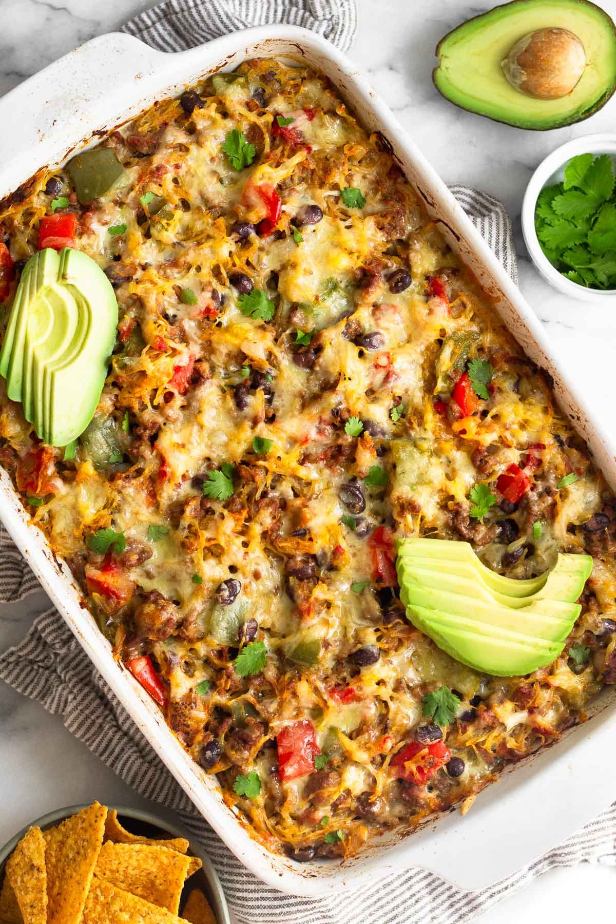 Healthy Chili Spaghetti Squash Casserole in a white casserole dish topped with slices of avocado - one of the recipes for this week's healthy weekly meal plan