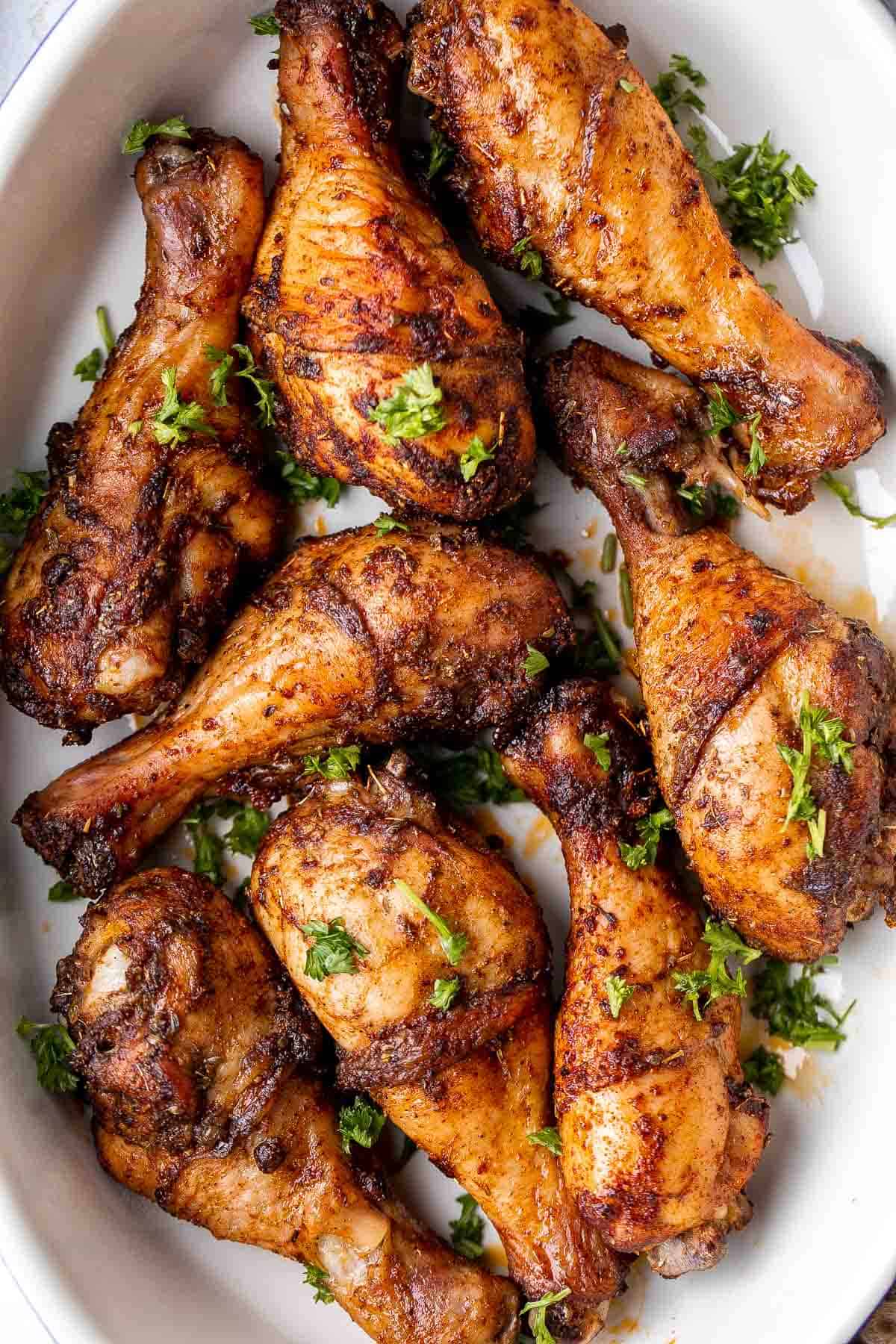 baked chicken drumsticks in a white dish topped with chopped fresh parsley - one of the recipes for this week's healthy weekly meal plan