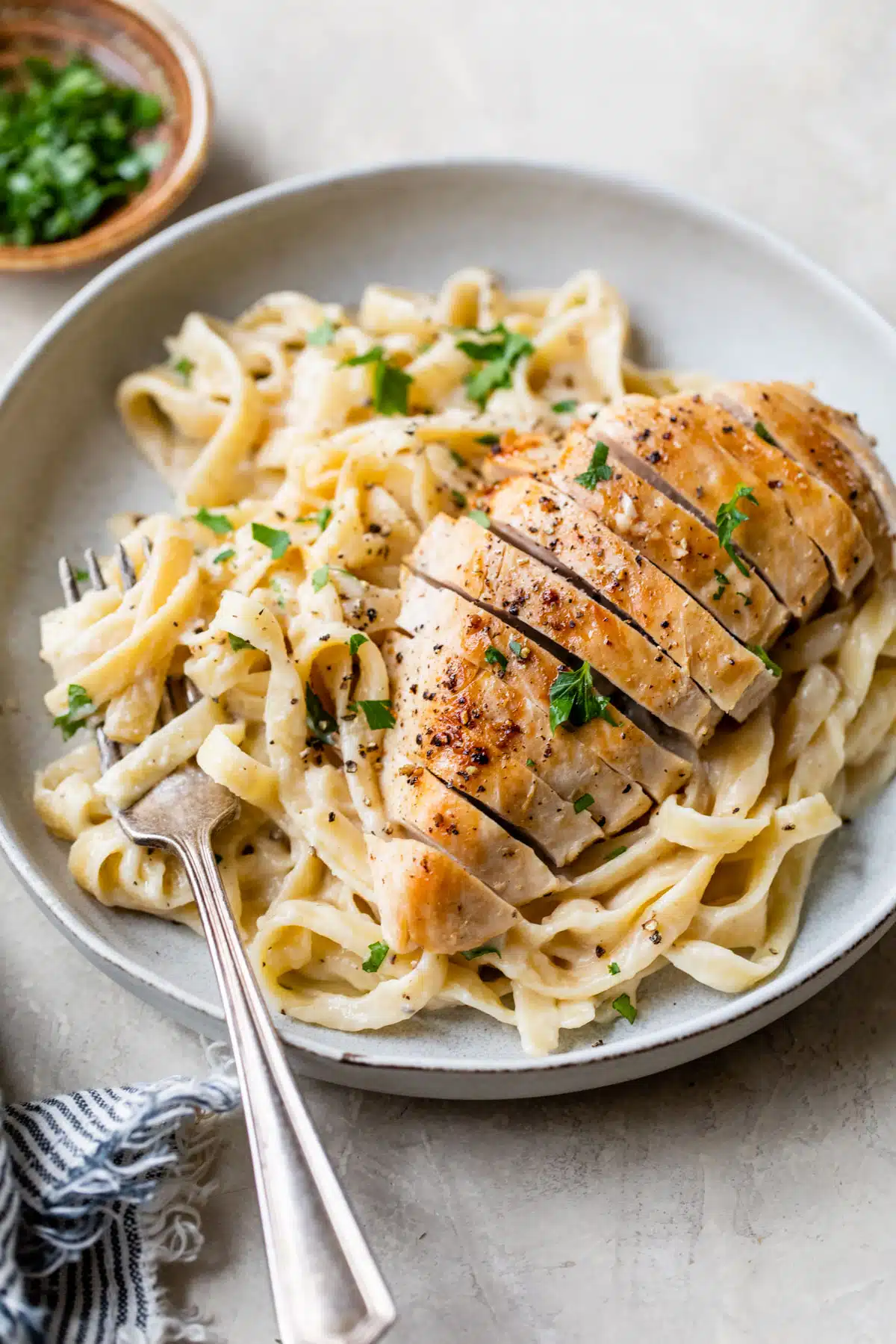 healthy fettuccine Alfredo with chicken on a gray plate with a fork - one of the recipe for this week's healthy weekly meal plan