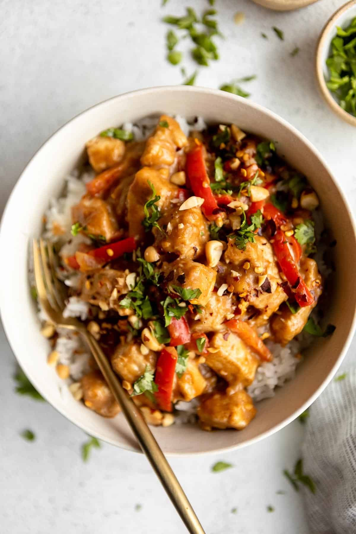 cooked peanut butter chicken with red peppers in a white bowl over white rice - one of the recipes for this week's healthy weekly meal plan