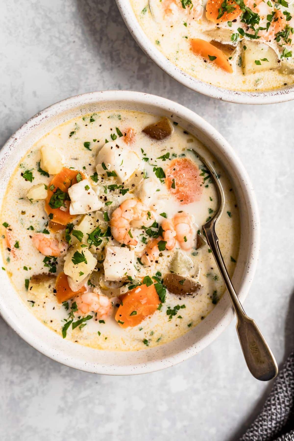 Healthy Seafood Chowder in a round white bowl with a spoon - one of the recipes for this week's healthy weekly meal plan