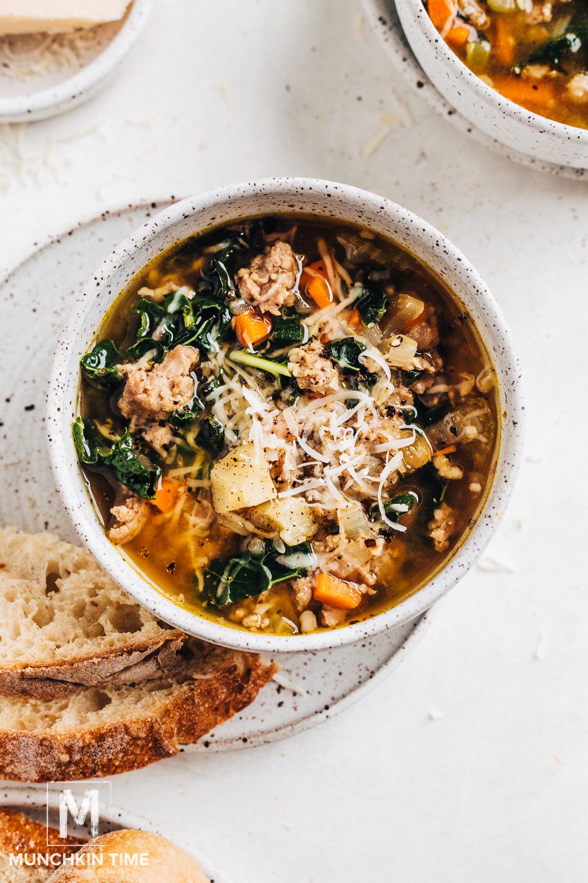healthy kale soup with sausage in a white bowl on top of a small plate with two slices of bread - one of the recipes for this week's healthy weekly meal plan