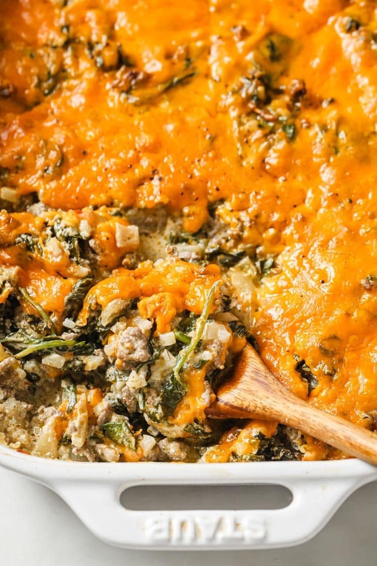 Cooked Cheesy Beef Casserole in a white baking dish with a wood spoon  - one of the recipes for this week's healthy weekly meal plan