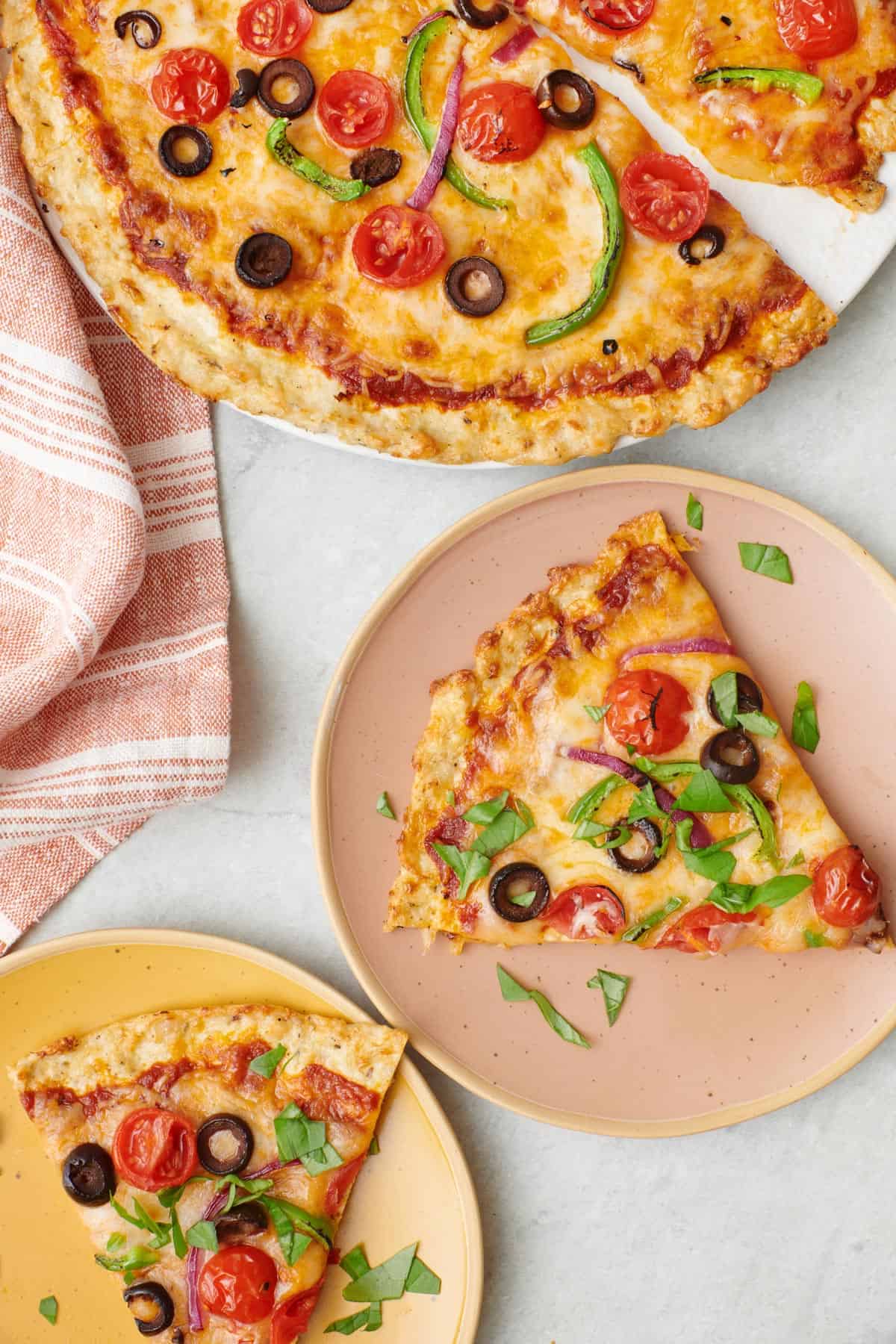 slices of chicken crust pizza on small plates topped with fresh chopped basil and sliced olives - one of the recipes for this week's healthy weekly meal plan