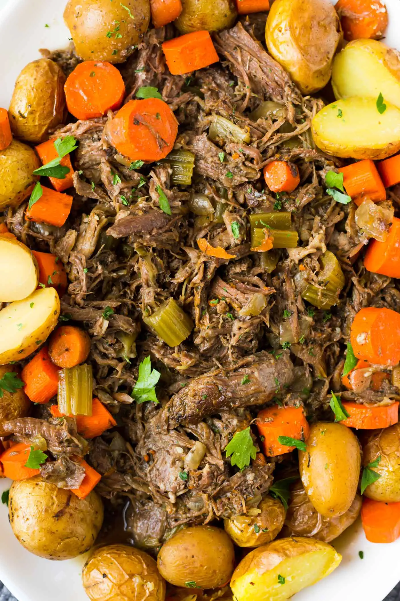 overhead shot of Whole30 pot roast on a platter with cooked carrots and potatoes