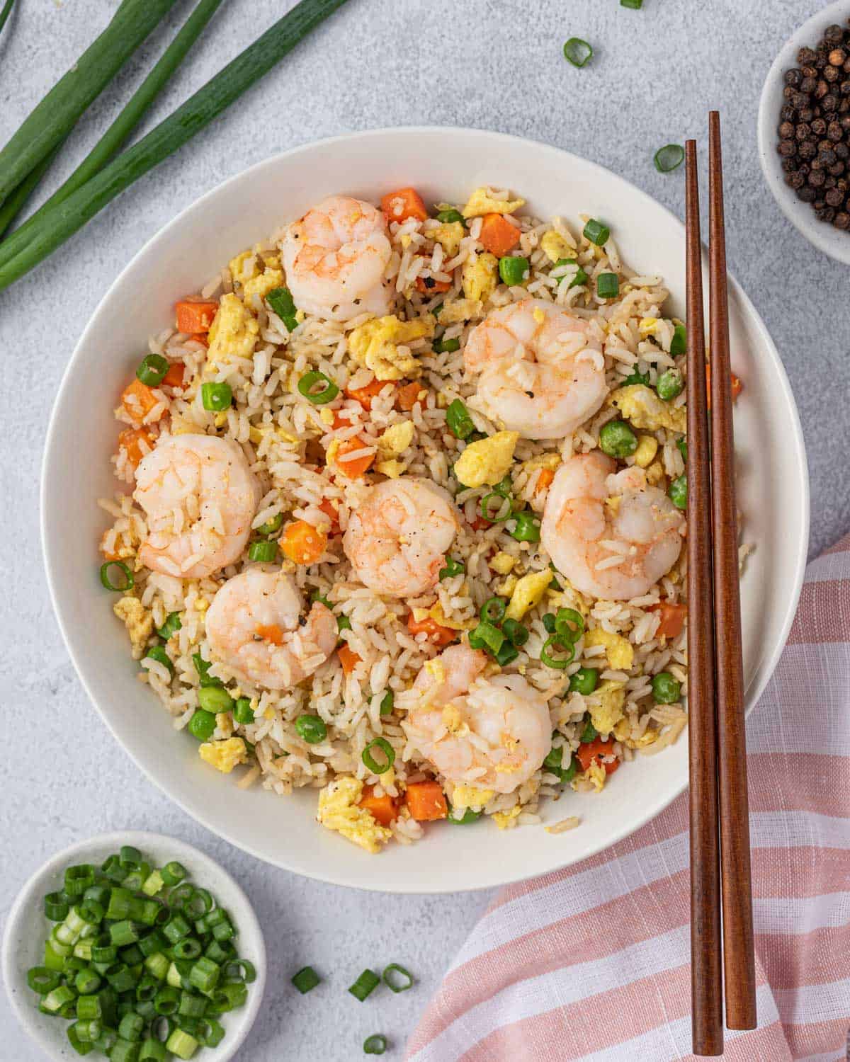 overhead shot of shrimp fried rice in a white bowl with chop sticks resting on the side - one of the recipes for this week's healthy weekly meal plan