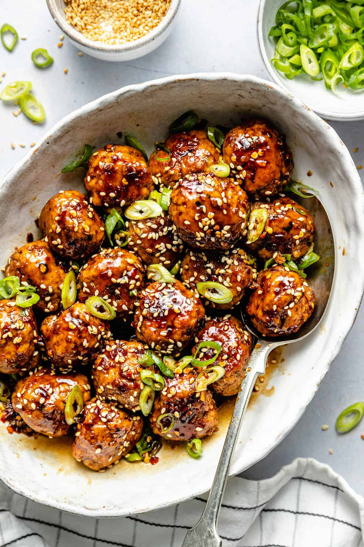 Healthy Sweet and Sticky Pork Meatballs in a white oval dish with a silver spoon - one of the recipes for this week's healthy weekly meal plan